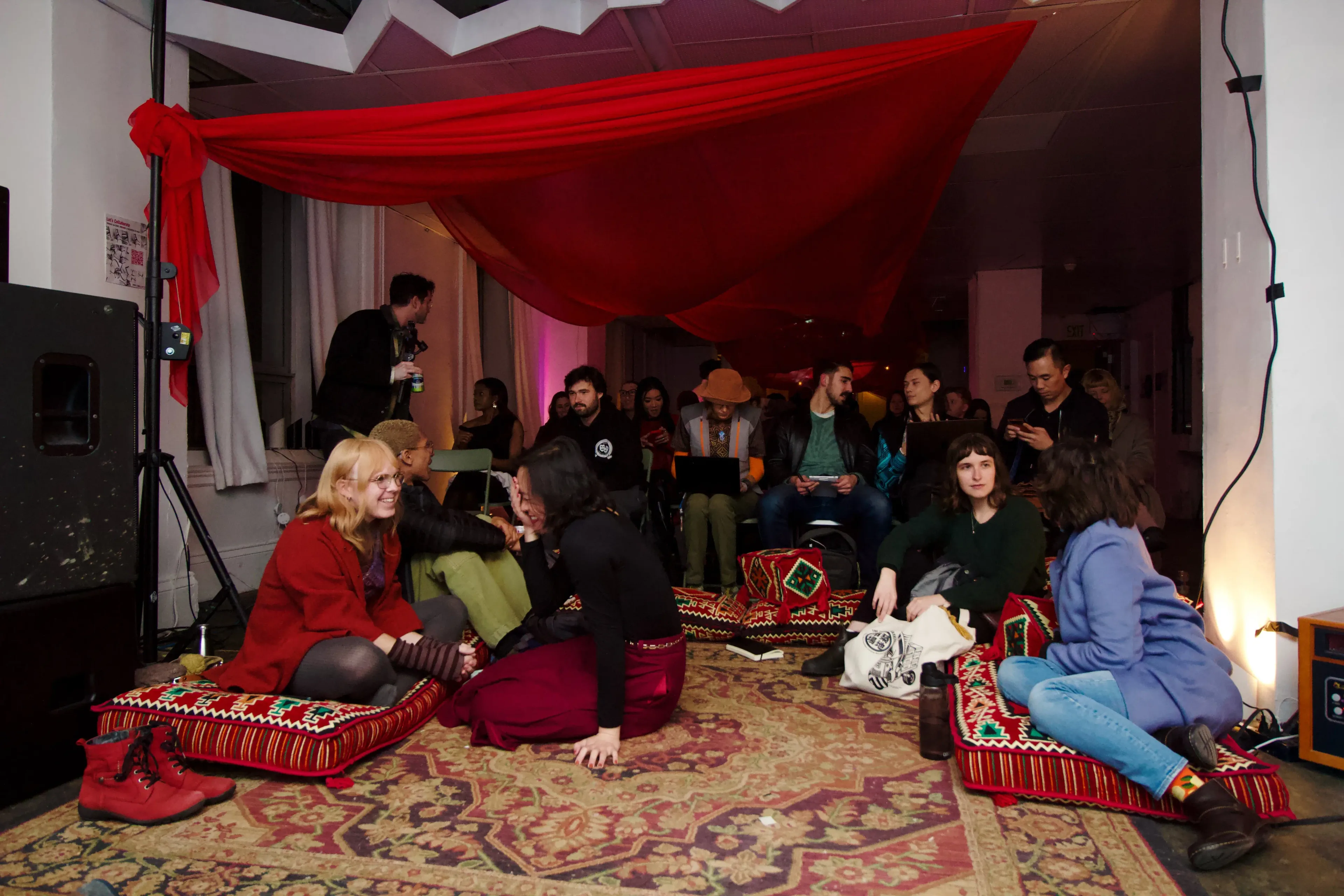 The room set up for Dreamshare, a red fabric canopy hung above rugs and low cushions